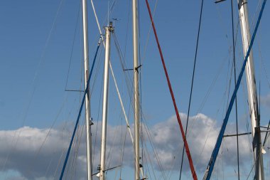 Mavi gökyüzüne karşı limanda direkler.