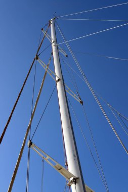 Mavi gökyüzüne karşı limanda direkler.