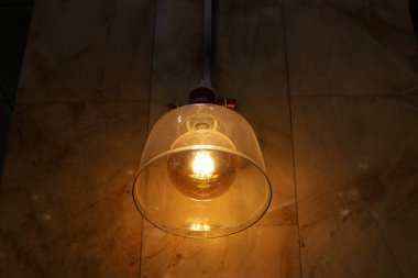 Odanın içini aydınlatan bir lamba tavanda asılı duruyor..