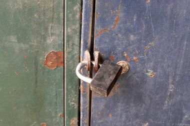 Çitte eski metal bir kilit asılı..