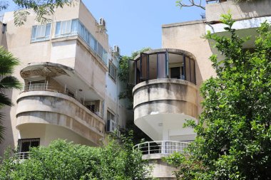 Şehirdeki bir caddede uzun bir ağacın tepesinden geçen bir bina..