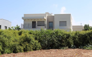 Köydeki ev arazisi yeşil ağaçlar ve çalılarla çevrili..