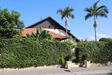 Köydeki ev arazisi yeşil ağaçlar ve çalılarla çevrili..