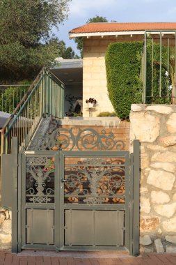 Köydeki ev arazisi yeşil ağaçlar ve çalılarla çevrili..