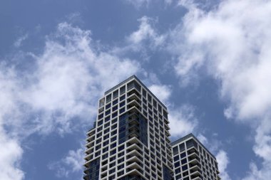 Büyük bir şehirde yüksek binaların üzerinde bulutlar.