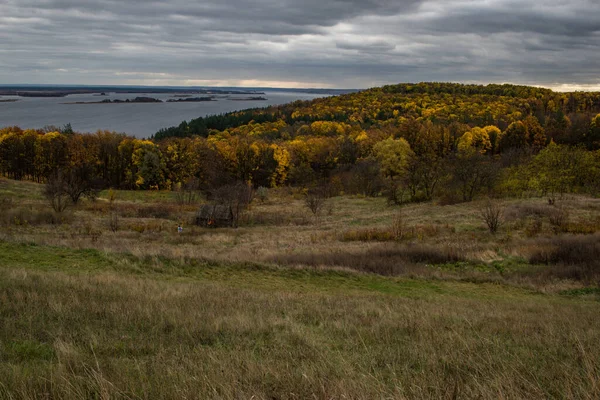 stock image Panoramic view of yellow trees, a wooden hut and the river on an autumn cloudy day.