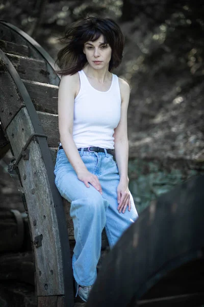 一个身穿白色T恤衫和蓝色牛仔裤的小女孩在一个乌克兰村庄前摆姿势 — 图库照片