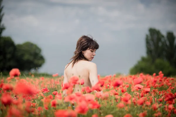 一个黑头发 光着肩膀的女孩在罂粟地里摆姿势 — 图库照片