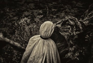 Beyaz bir battaniyeye sarılı bir insanın monokromatik görüntüsü doğanın bir arka planına karşı..