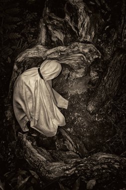 Beyaz bir battaniyeye sarılı bir insanın monokromatik görüntüsü doğanın bir arka planına karşı..