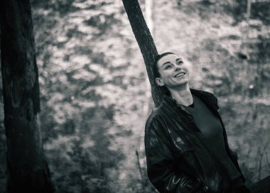 Bahar ormanında poz veren lastik çizmeli bir kız, çiçek açan ağaçlar ve canlı yeşilliklerle çevrili, doğanın yenilenmesinin özünü yayıyor..