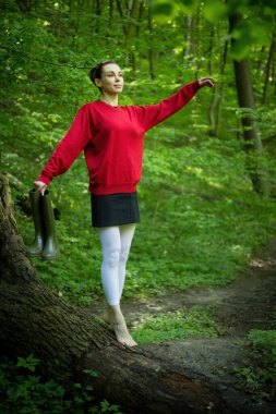 Bahar ormanında poz veren lastik çizmeli bir kız, çiçek açan ağaçlar ve canlı yeşilliklerle çevrili, doğanın yenilenmesinin özünü yayıyor..