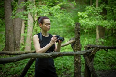 Kameralı bir kız yemyeşil ormanı keşfediyor, kamerasının merceğiyle güzelliğini yakalıyor.
