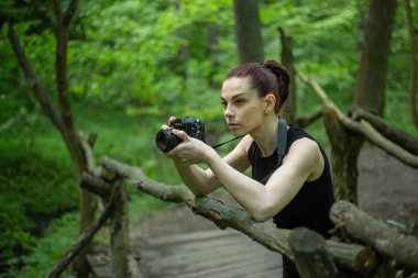 Kameralı bir kız yemyeşil ormanı keşfediyor, kamerasının merceğiyle güzelliğini yakalıyor.