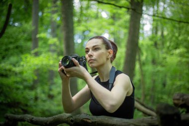 Kameralı bir kız yemyeşil ormanı keşfediyor, kamerasının merceğiyle güzelliğini yakalıyor.