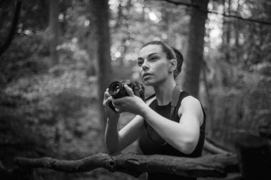 Kameralı bir kız yemyeşil ormanı keşfediyor, kamerasının merceğiyle güzelliğini yakalıyor.