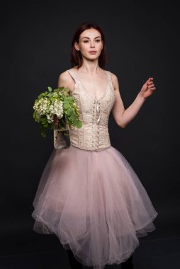 Büyüleyici bir kadın fotoğraf stüdyosunda bir akasya dalıyla poz veriyor..