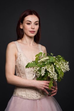 Büyüleyici bir kadın fotoğraf stüdyosunda bir akasya dalıyla poz veriyor..