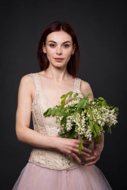 Büyüleyici bir kadın fotoğraf stüdyosunda bir akasya dalıyla poz veriyor..