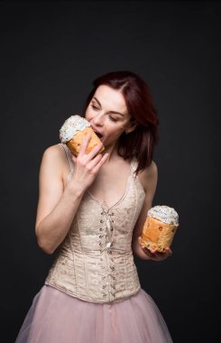 Çekici bir kadın bir elinde Paskalya pastası, diğer elinde bir tabanca ve yanına da bir pala ile poz vererek çarpıcı ve alışılmadık bir görüntü yaratıyor..