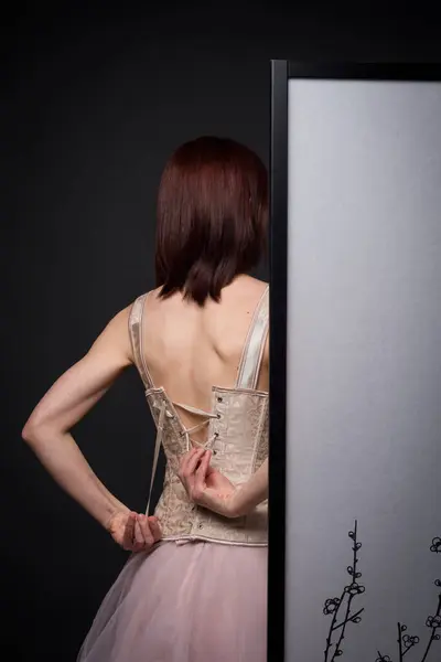 Çekici bir kız aynanın yanındaki fotoğraf stüdyosunda poz verirken, bir fotoğrafçı onun resmini çekiyor, güzellik, zarafet ve profesyonel sanatla dolu bir sahne yaratıyor..