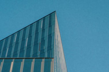 Gökyüzüne karşı modern binaların parçaları, parlak çizgiler, cam yansımalar ve kalın mimari detaylar yakalıyor, kentsel tasarımı ufkun açık genişliğiyle harmanlıyor..
