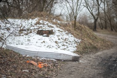 Doğada insanların bıraktığı çöp: plastik şişeler, poşetler, ambalajlar ve araba parçaları.