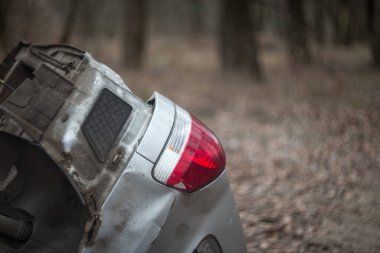 Doğada insanların bıraktığı çöp: plastik şişeler, poşetler, ambalajlar ve araba parçaları.