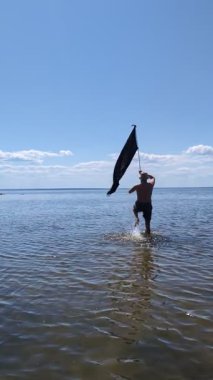 Siyah bayraklı adam denize koşuyor..