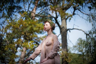 Sonbahar ormanında sarı yapraklı çıplak bir kadın..