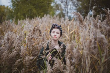 Sonbahar günbatımında nehir kamışlarının arasında üstsüz bir kadın duruyor..