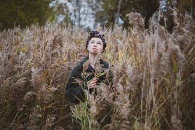 Sonbahar günbatımında nehir kamışlarının arasında üstsüz bir kadın duruyor..