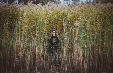 Sonbahar günbatımında nehir kamışlarının arasında üstsüz bir kadın duruyor..