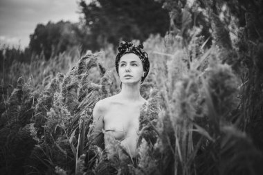 Sonbahar günbatımında nehir kamışlarının arasında üstsüz bir kadın duruyor..