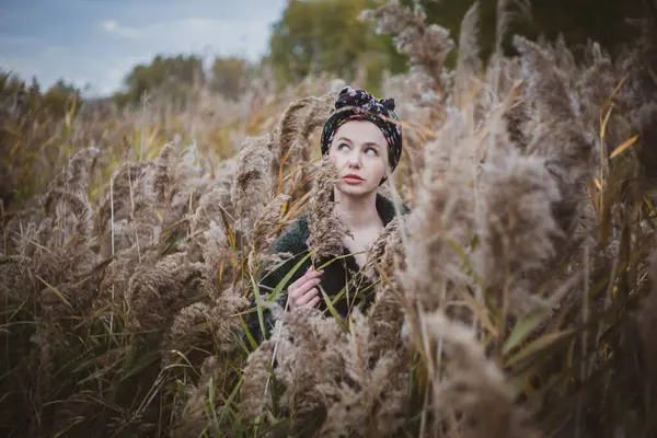 Sonbahar günbatımında nehir kamışlarının arasında üstsüz bir kadın duruyor..