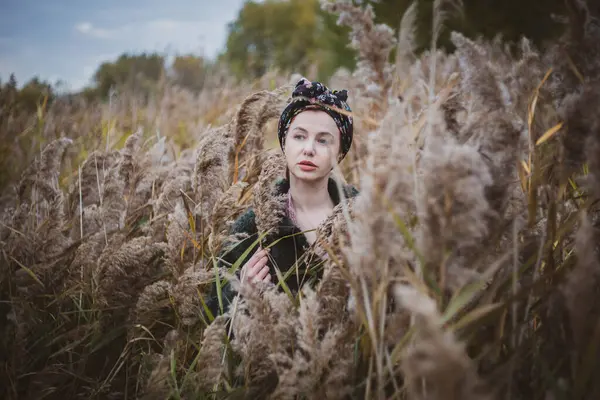 Sonbahar günbatımında nehir kamışlarının arasında üstsüz bir kadın duruyor..