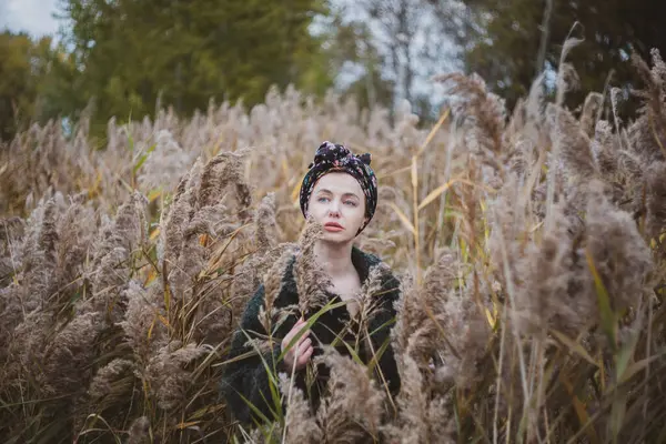 Sonbahar günbatımında nehir kamışlarının arasında üstsüz bir kadın duruyor..