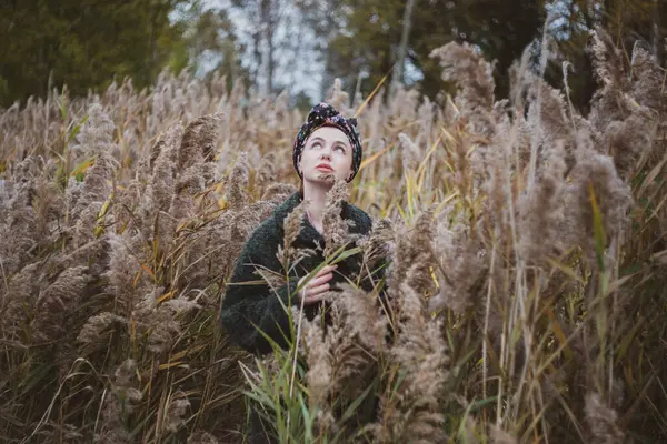 Sonbahar günbatımında nehir kamışlarının arasında üstsüz bir kadın duruyor..