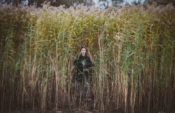 Sonbahar günbatımında nehir kamışlarının arasında üstsüz bir kadın duruyor..