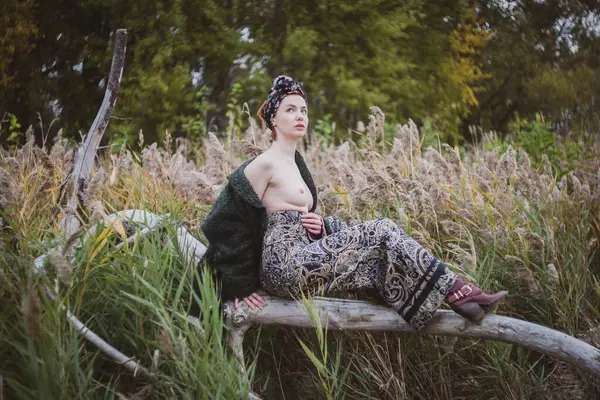 Sonbahar günbatımında nehir kamışlarının arasında üstsüz bir kadın duruyor..