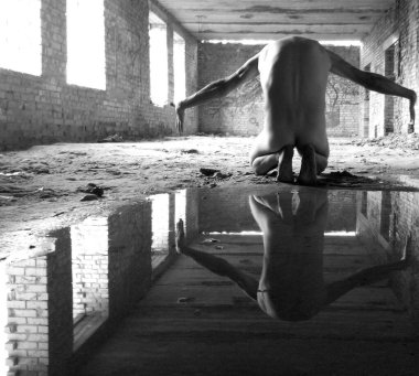 Ham duygusal durgunlukla tuğlalarla çerçevelenmiş çıplak figür..