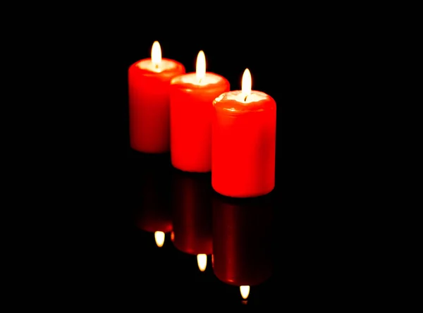 Τρία Ζεστά Κόκκινα Κεριά Αντανακλώνται Στο Φόντο Ενός Μαύρου Καθρέφτη — Φωτογραφία Αρχείου