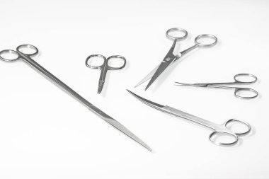 A set of various scissors for a hairdresser on a light background with a reflection in a white mirror table