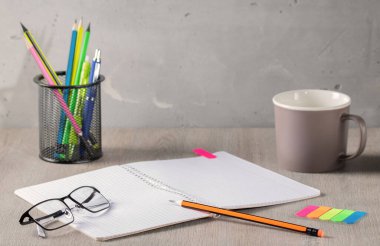 Office supplies - pencils, notepad, glasses and pencil case are on the office desk. Cozy working environment