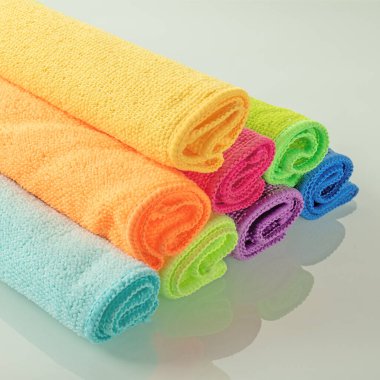 Ayna arka planında parlak renklerde mutfak mikrofiber havluları yığını.