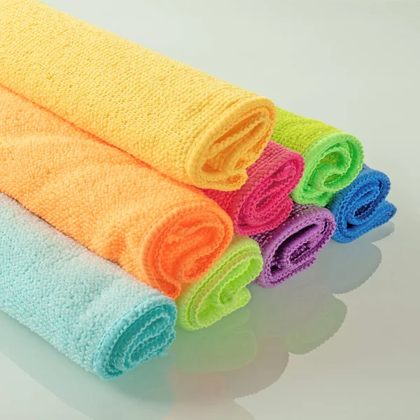 Ayna arka planında parlak renklerde mutfak mikrofiber havluları yığını.