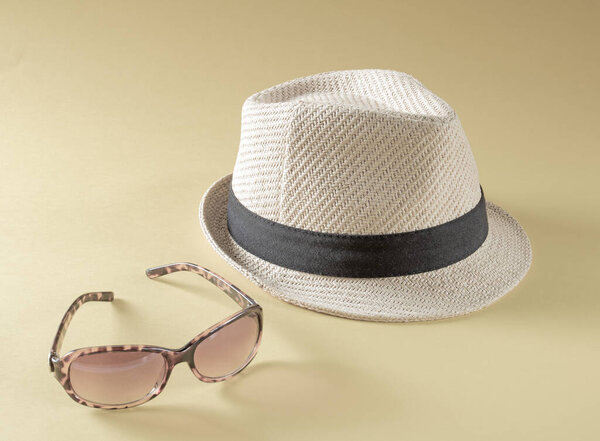 Summer holiday accessories.Straw hat and sunglasses on sepia toned background.