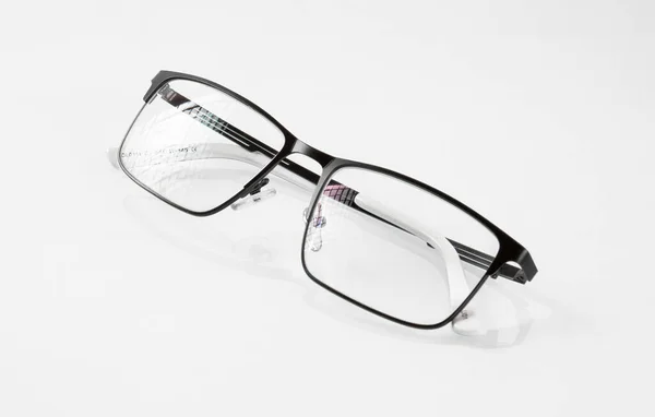 ブラックメタルフレームのメガネは ホワイトミラーの背景に反射され レンズにグレアがあります — ストック写真