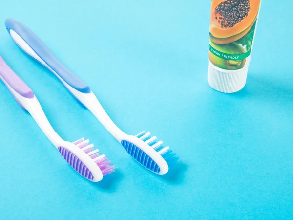 Zwei Mehrfarbige Kunststoffzahnbürsten Und Eine Tube Umweltfreundliche Zahnpasta Auf Blauem — Stockfoto