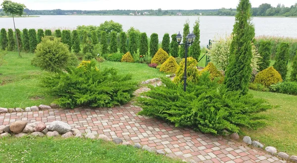 Garden design. Tile path in an ornamental garden among lush vegetation